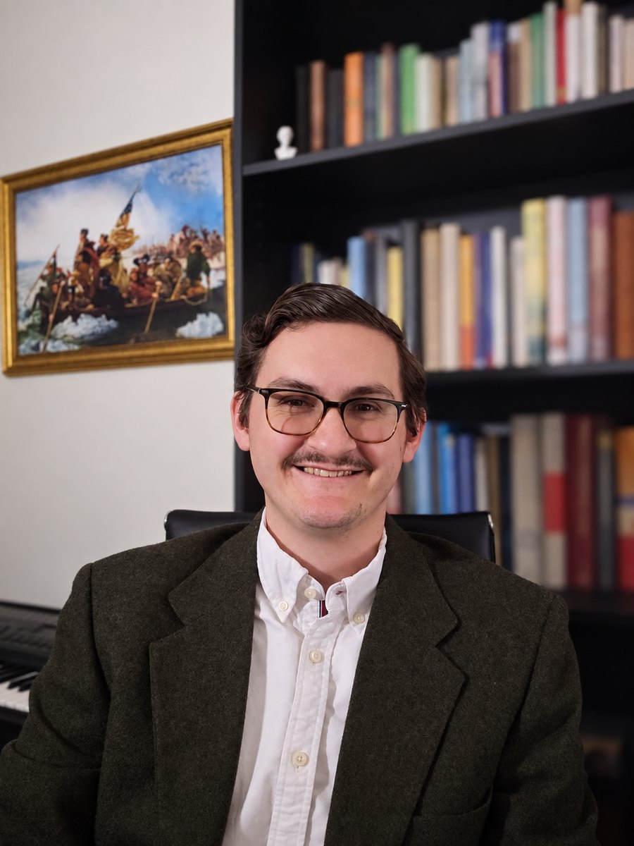 Andrew Wilson, tutor, smiling at the camera in a dark tweed jacket and white shirt
