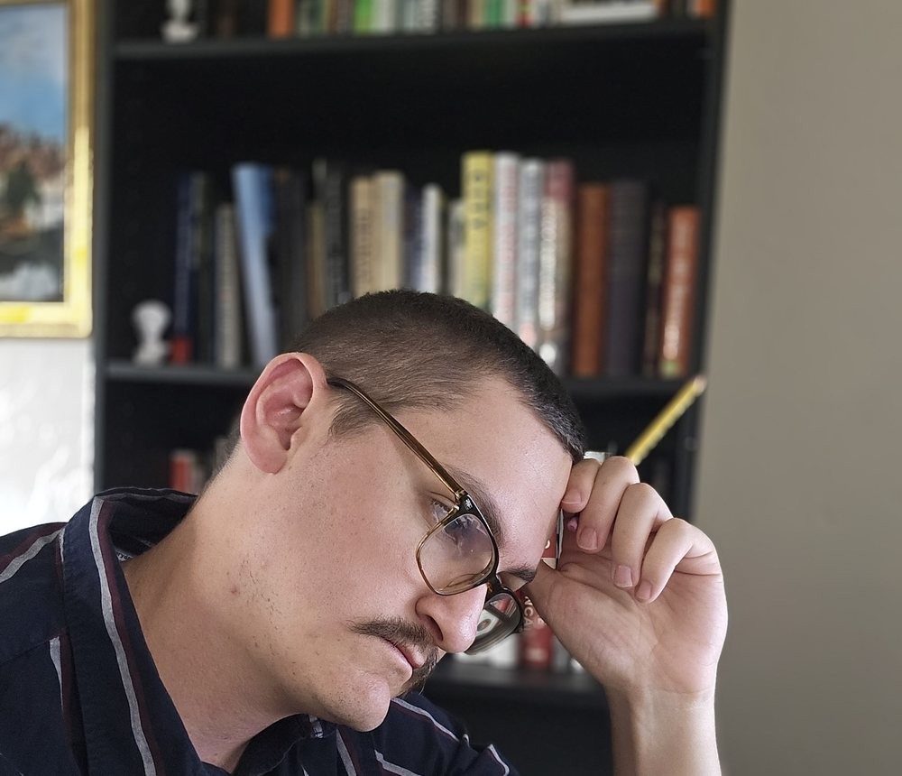 Andrew Wilson resting his head on one hand while reading an open book