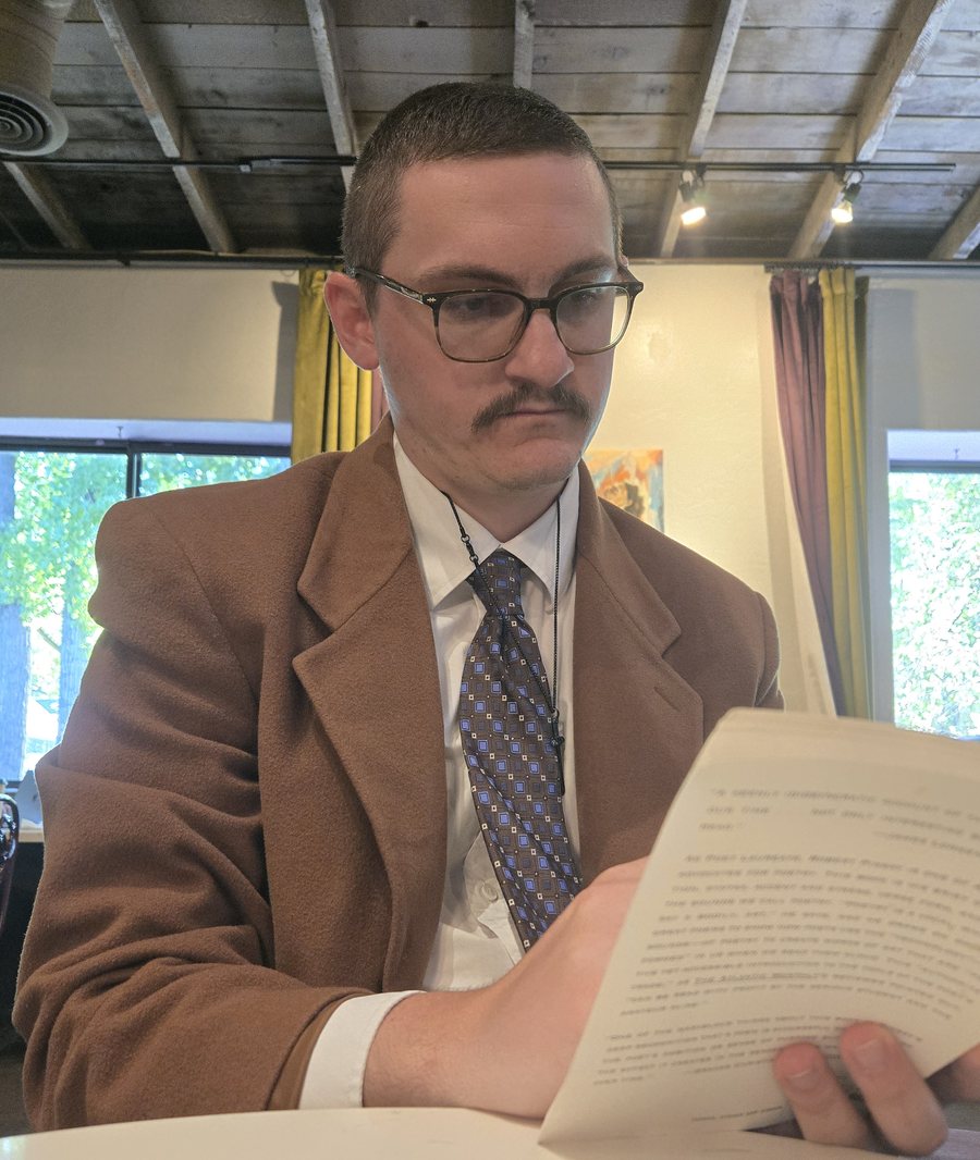 Andrew Wilson reading a printed page at a table in a Prescott café